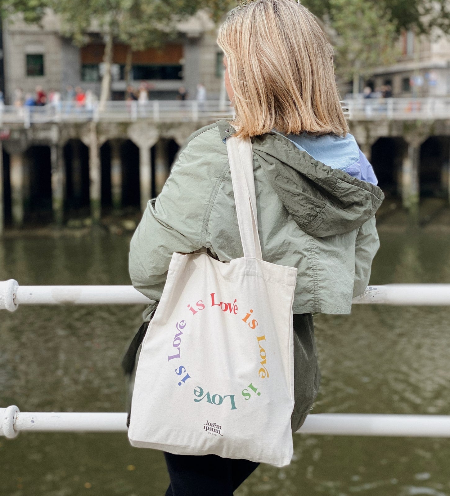 Bolsa Tote Bag de loneta en color natural con mensaje "love is love" multicolor en circulo. Fabricada con algodón orgánico y materiales reciclados. Ideal para llevar encima todo aquello que necesitamos. Dimensiones: 37x39cm