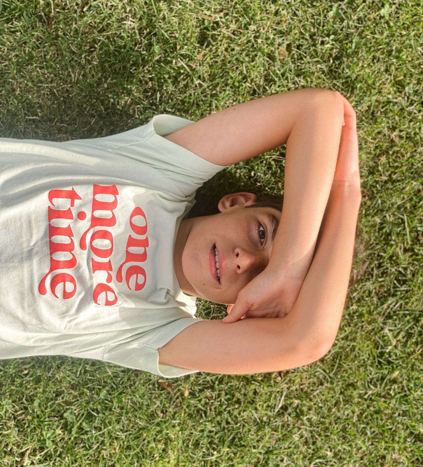 Camiseta de algodón orgánico para niños con mensaje one more time. 100% sostenible. Camiseta básica en verde claro con mensaje one more time en la parte delantera en rojo anaranjado.